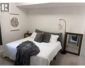A bedroom with a white bed and a grey blanket.