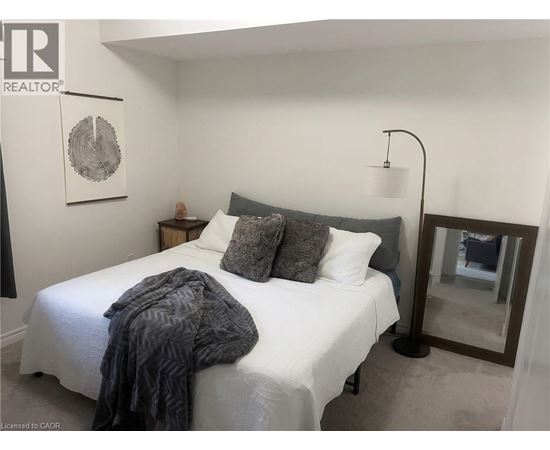 A bedroom with a white bed and a grey blanket.