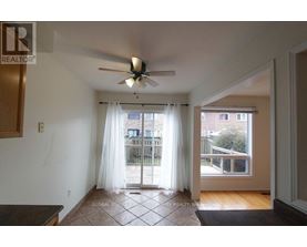 A room with a ceiling fan and sliding glass doors leading to a balcony.