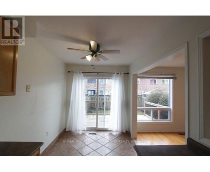 A room with a ceiling fan and sliding glass doors leading to a balcony.