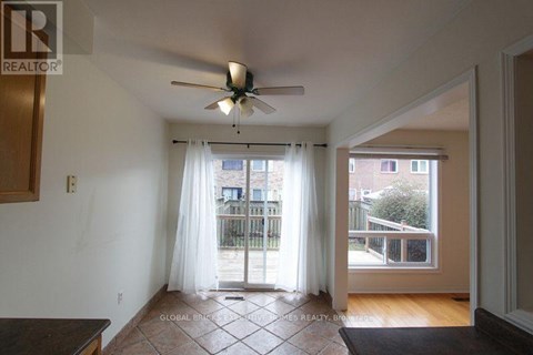 A room with a ceiling fan and sliding glass doors leading to a balcony.
