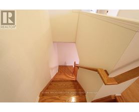 A wooden staircase with a white wall on the side.