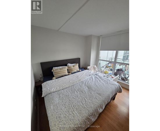 A bedroom with a large bed and a window overlooking a city.