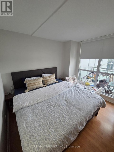A bedroom with a large bed and a window overlooking a city.