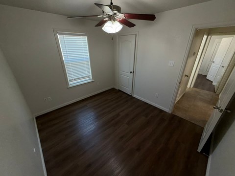 A room with a ceiling fan and wooden flooring.