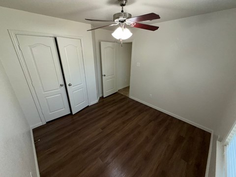 A room with a ceiling fan and wooden floors.