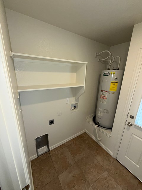 A room with a water heater and a door.
