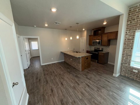 A kitchen with a wooden island and a brick wall.
