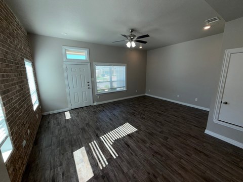 A room with a ceiling fan and wooden flooring.