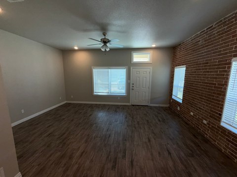 A room with a ceiling fan and wooden flooring.