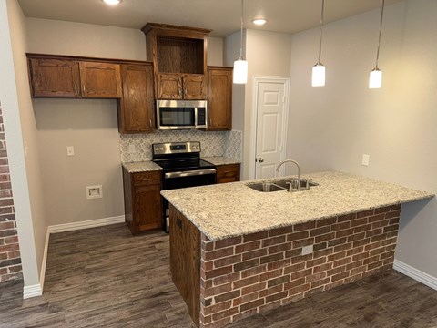 A kitchen with a brick wall and wooden cabinets.