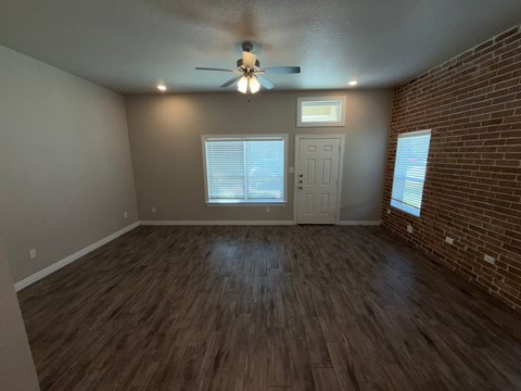 A room with a ceiling fan and wooden flooring.
