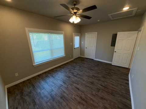 A room with a ceiling fan and a window with blinds.