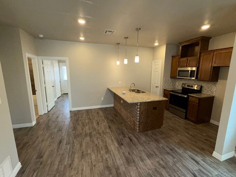 A kitchen with a granite counter top and wooden cabinets.