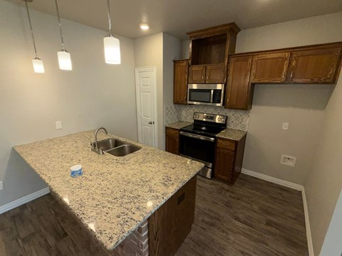 A kitchen with granite countertops and wooden cabinets.