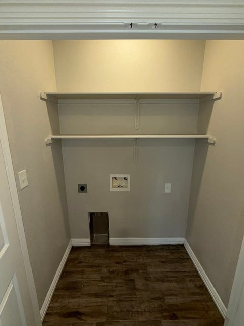 A room with a wooden floor and a white wall with a shelf above it.