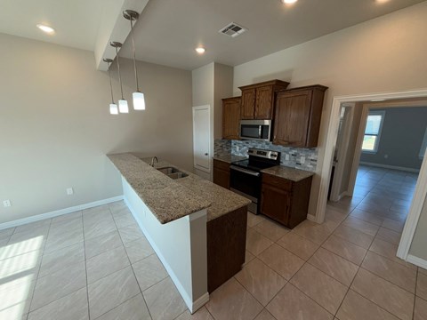 A kitchen with a granite countertop and wooden cabinets.