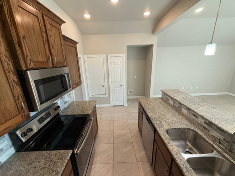 A kitchen with granite countertops and wooden cabinets.