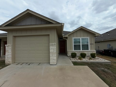 A house with a garage and a driveway in front.