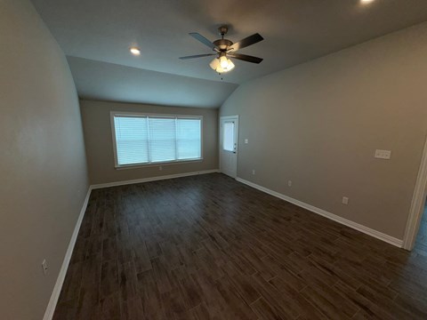 A room with a ceiling fan and wooden flooring.