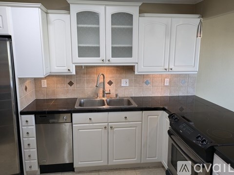 A kitchen with white cabinets and a black countertop.