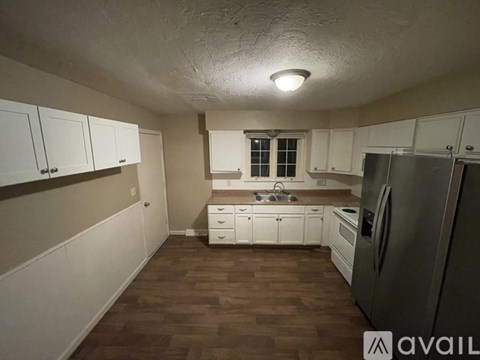 A kitchen with white cabinets and a black fridge.