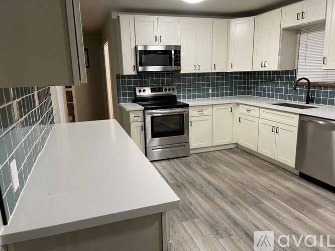 A kitchen with a white countertop and a tile backsplash.
