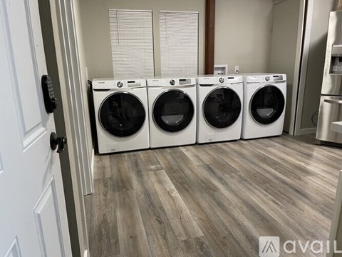 Four front load washing machines are lined up in a laundry room.