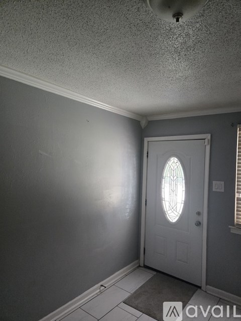 A white door with a glass window is set in a grey wall.