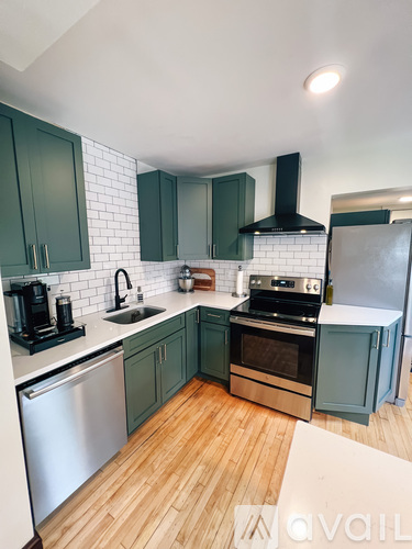 A kitchen with green cabinets and a white backsplash.