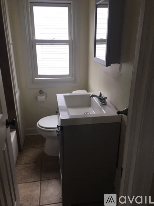 A bathroom with a toilet, sink, and window.
