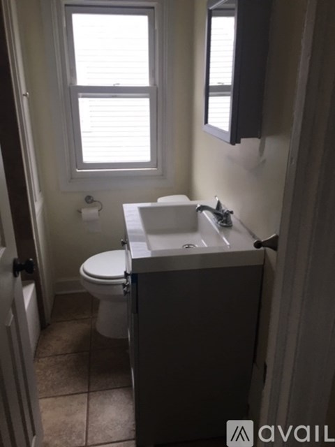 A bathroom with a toilet, sink, and window.