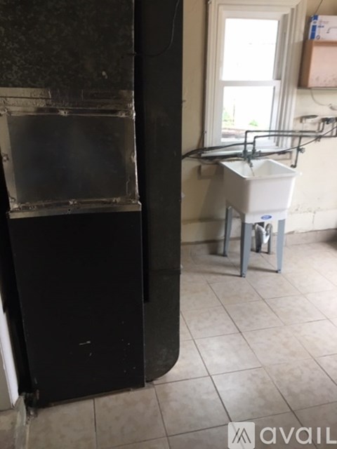 A black refrigerator sits in a kitchen next to a white dishwasher.
