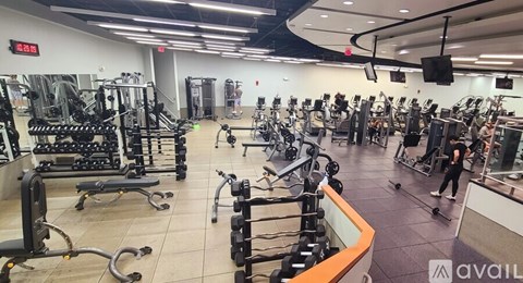 A gym with a variety of equipment including treadmills, weights, and exercise machines.