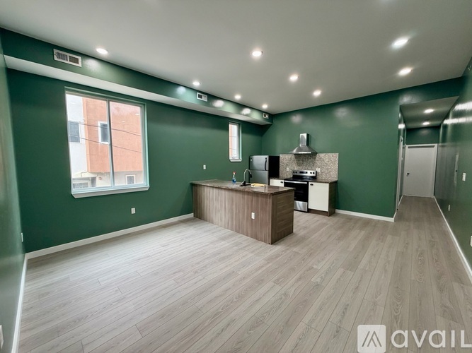 A spacious room with a green wall and a wooden floor.