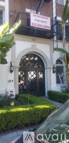 A white building with a black door and a sign that says "Apartment for Rent".