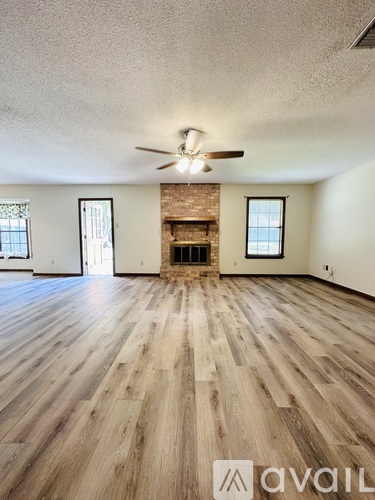 A room with wooden flooring and a fireplace.
