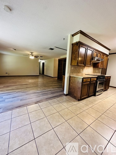 A kitchen area with tile flooring and wooden cabinets.