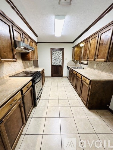A kitchen with brown cabinets and a tiled floor.
