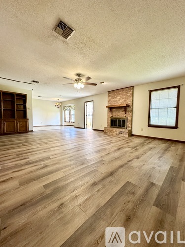 A spacious room with wooden flooring and a ceiling fan.