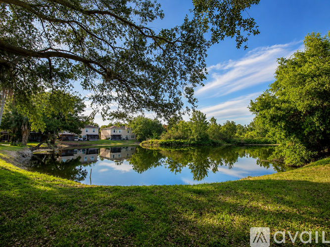 A serene lake surrounded by lush greenery and trees under a clear blue sky.