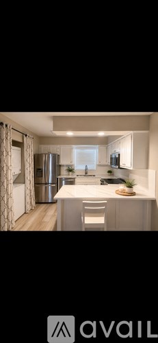 A modern kitchen with a white countertop and stainless steel appliances.