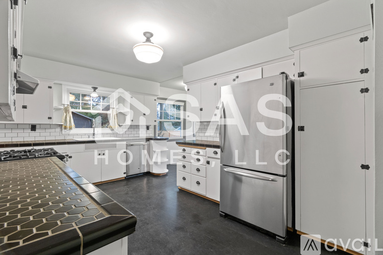 A modern kitchen with stainless steel appliances and a black countertop.