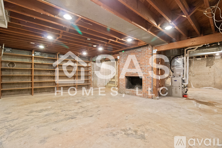 A large empty room with wooden beams and a brick fireplace.