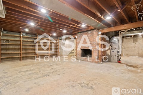 A large empty room with wooden beams and a brick fireplace.