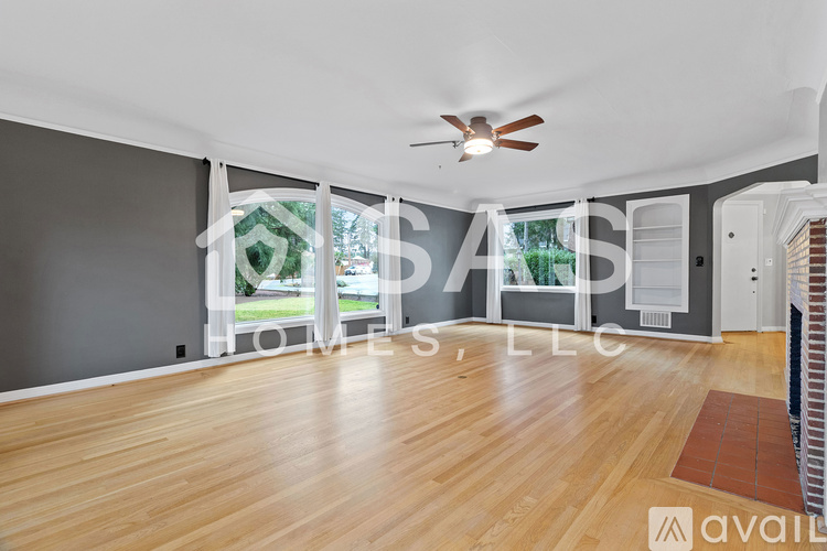 A spacious room with wooden flooring and a ceiling fan.