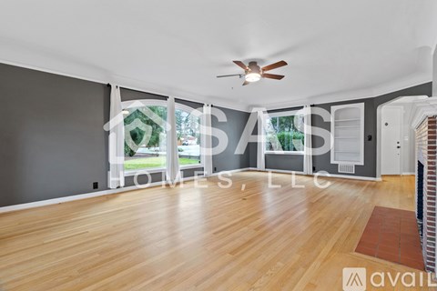 A spacious room with wooden flooring and a ceiling fan.