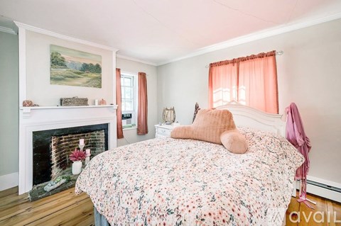 A bedroom with a floral bedspread and a fireplace.