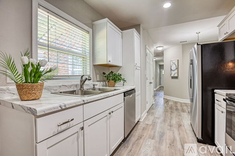 A kitchen with white cabinets and a black refrigerator.