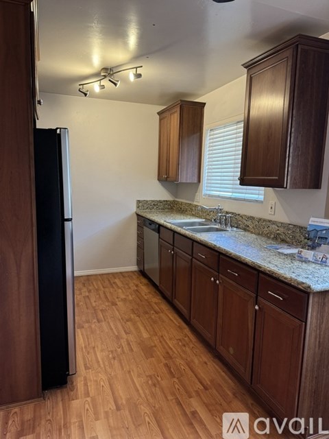 A kitchen with wooden cabinets and a black refrigerator.